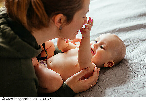Adorable naked baby examines mother's face