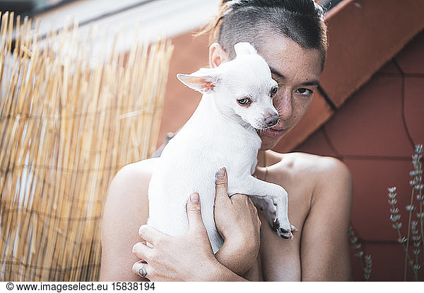 adorable portrait of strong woman cuddling dog close to face on balcon