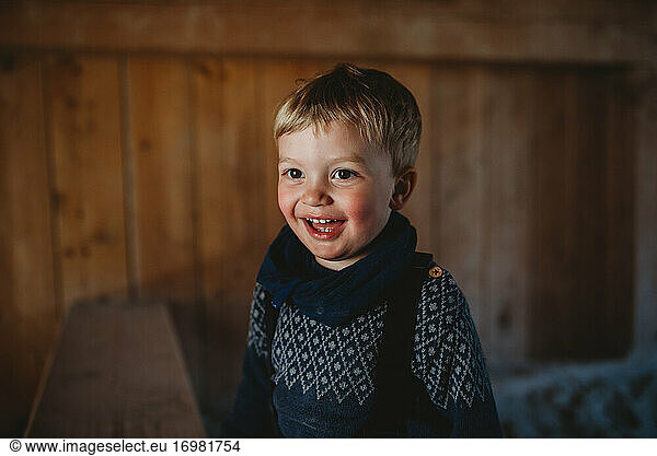 Adorable young boy smiling in a wooden cabin in winter