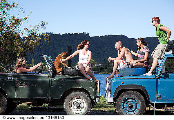 Adult friends chatting on top of off road vehicles  Lake Okareka  New Zealand