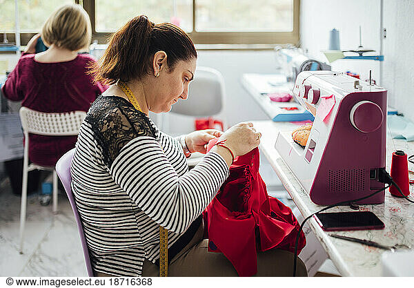Adult woman using a sewing machine in a sewing workshop