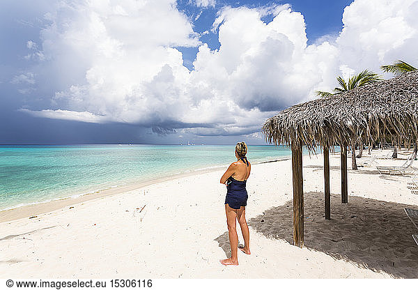 Adult woman watching approaching storm clouds from a beach