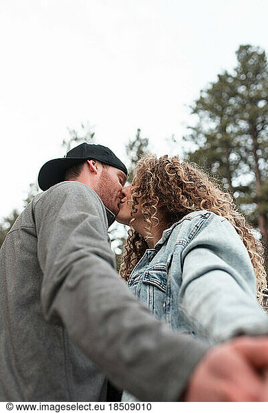 Adventurous Young Couple Kissing in Colorado Mountains in Winter