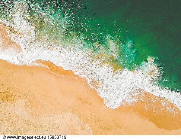Aerial Drone Shot of ocean waves crashing on sandy beach