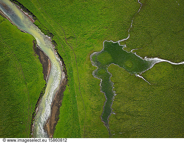 aerial shot from river running through green field