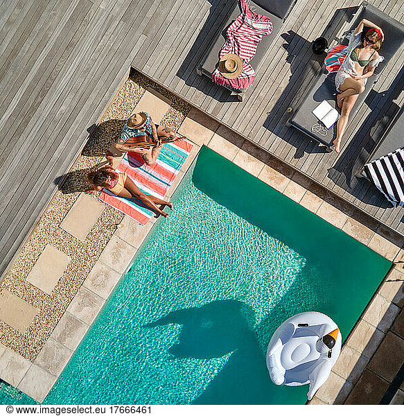Aerial view friends relaxing at sunny summer poolside