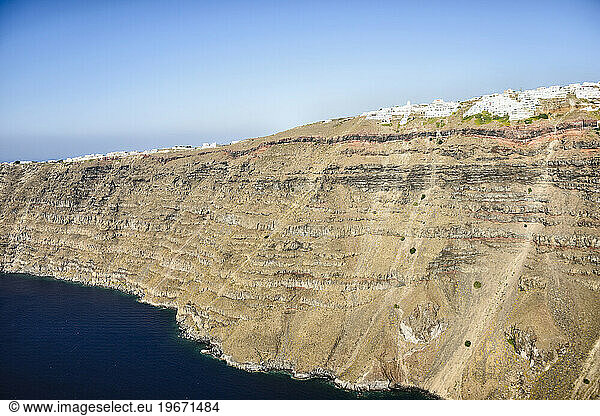 Aerial view of a town at the top of a sheer cliff on the island of Egeo  whitewashed houses on the clifftop.