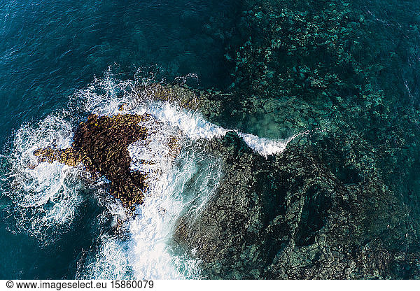 Aerial view of a wave breaking over a sharp lava reef in Tenerife.