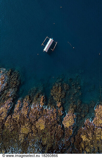Aerial view of banca boat near rocky coastline