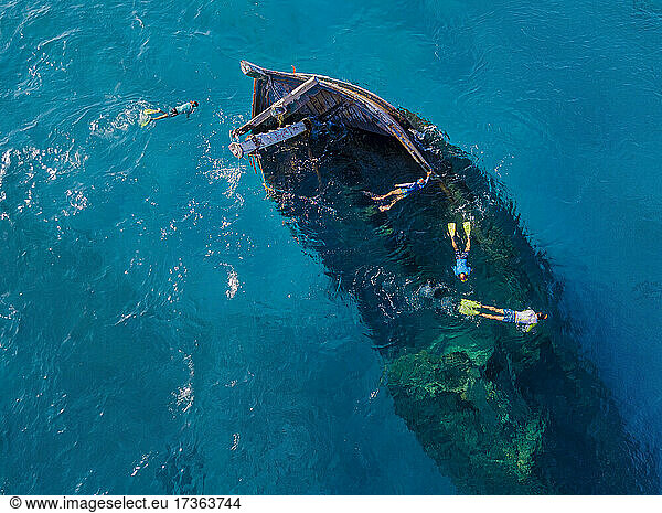 Aerial view of four men snorkeling around sunken shipwreck