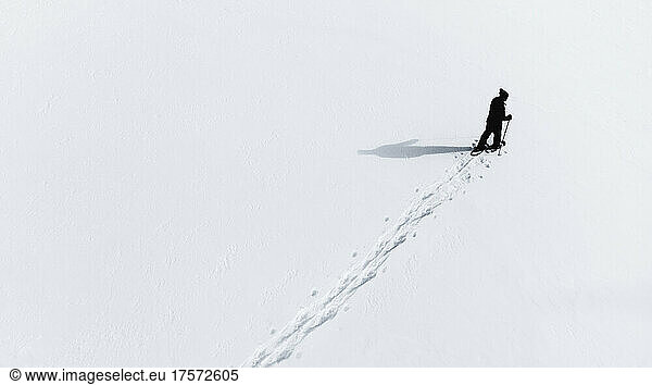 Aerial view of man snowshoeing across an empty snowy landcsape.