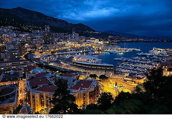Aerial view of Monaco Monte Carlo harbour and illuminated city skyline in the evening blue hour twilight. Monaco Port night view with luxurious yachts
