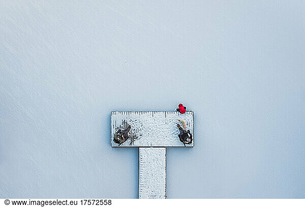 Aerial view of people sitting on snowy dock on frozen lake in winter.