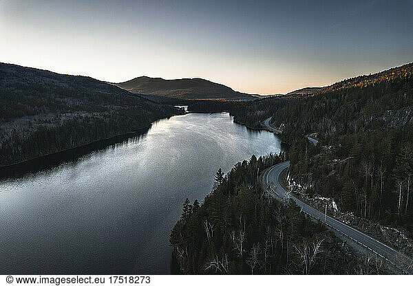 aerial view of road winding along lake in Maine mountains