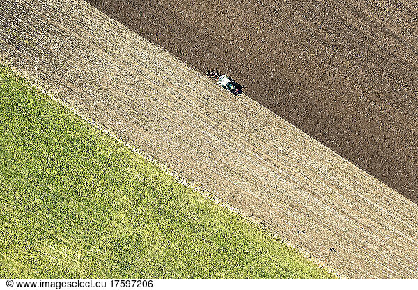 Aerial view of tractor plowing field on sunny day