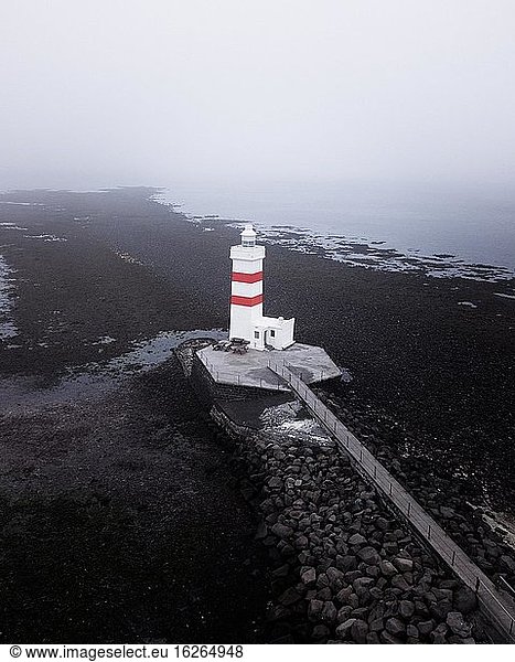 Aerial view  red and white lighthouse Garður Old Lighthouse  black lava beach  Iceland  Europe