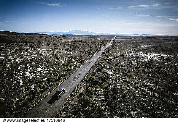 aerial view single truck on long straight road in desert landscape