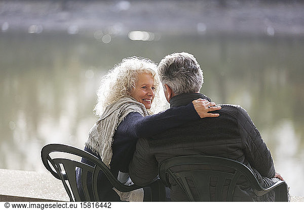 Affectionate active senior couple hugging at park pond