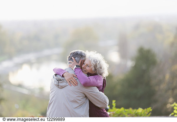 Affectionate active senior couple hugging in nature