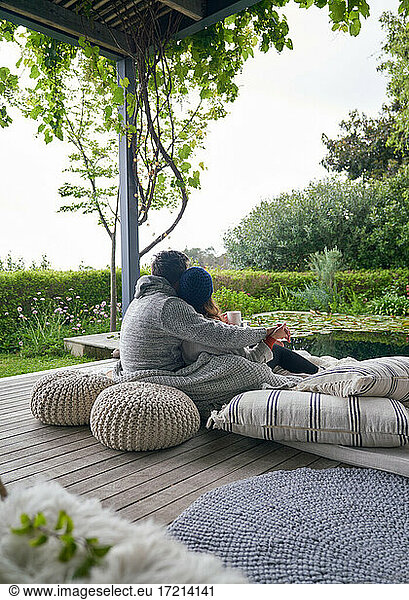 Affectionate couple cuddling on cushions on luxury patio