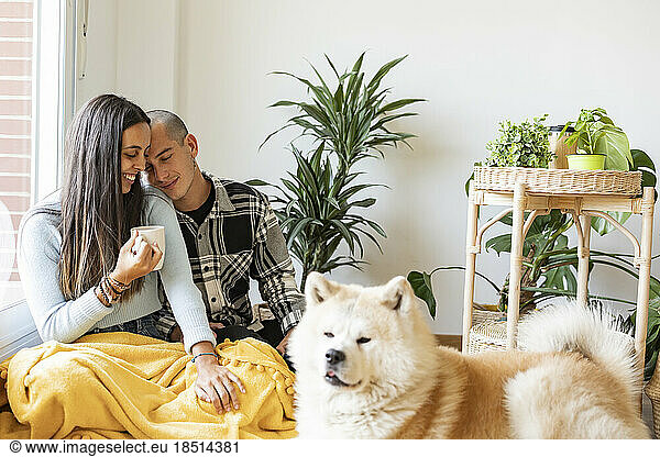 Affectionate couple having coffee with dog in foreground