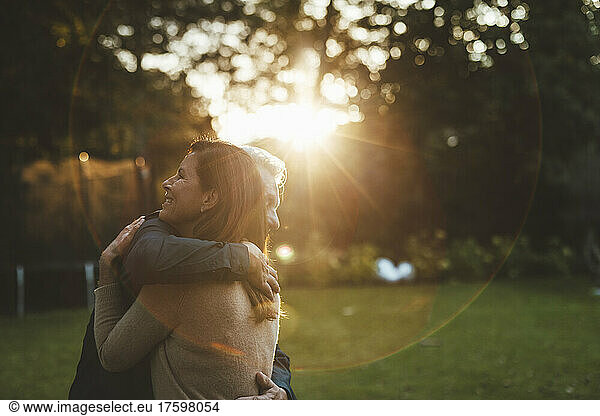 Affectionate couple hugging at backyard sunset
