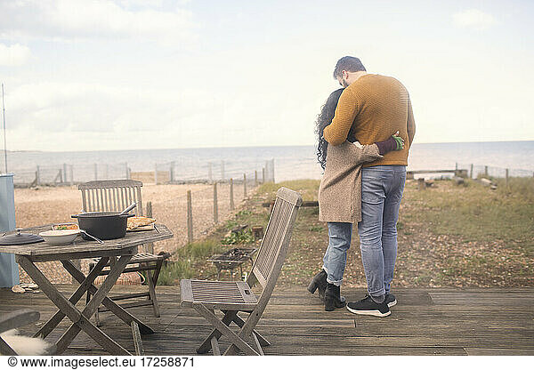 Affectionate couple hugging on ocean beach patio