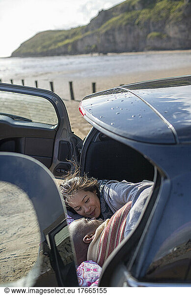 Affectionate couple laying in back of car on beach
