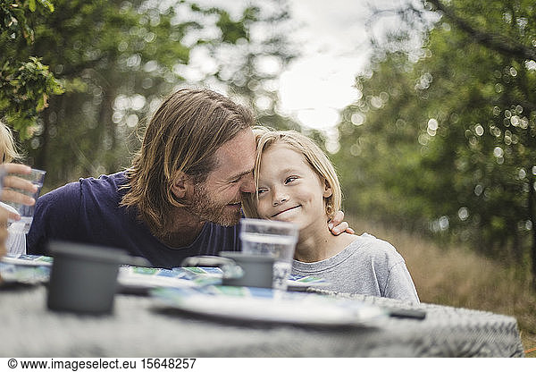 Affectionate father embracing daughter at table in campsite