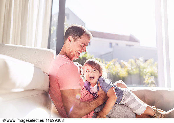 Affectionate father holding baby son in sunny living room