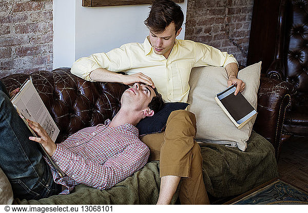 Affectionate gay couple relaxing on sofa at home