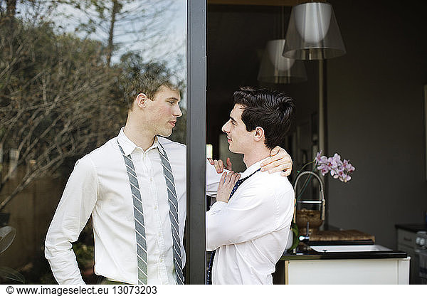 Affectionate gay couple standing at doorway
