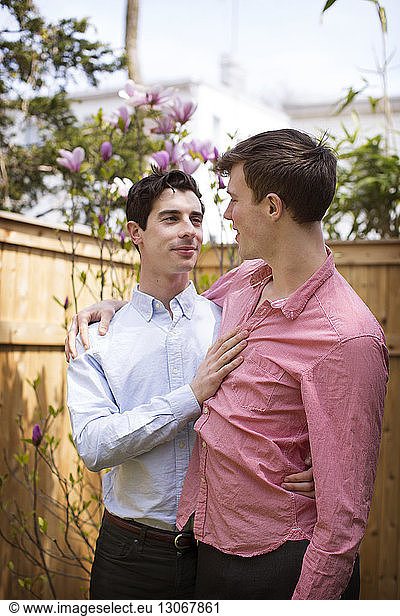 Affectionate gay couple standing in backyard