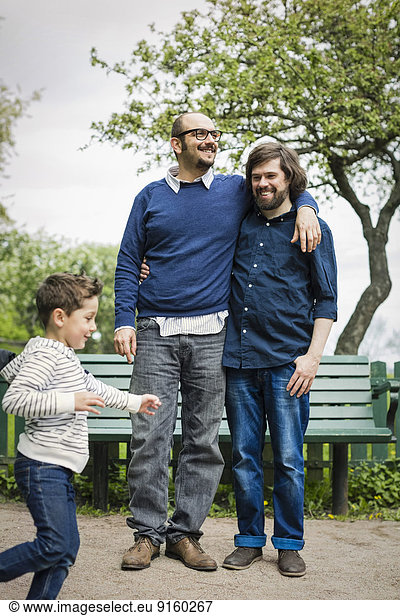 Affectionate gay couple with son playing in park