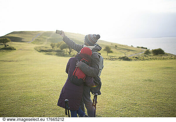 Affectionate hiker couple taking selfie in sunny grass