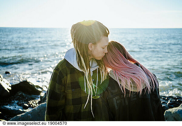 Affectionate lesbian couple standing near sea