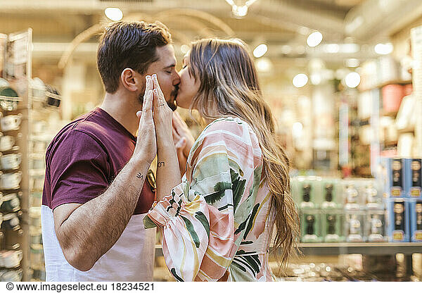 Affectionate man and woman kissing each other in store