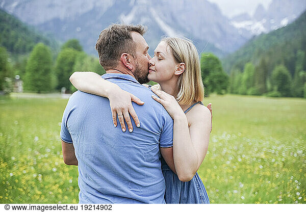 Affectionate man kissing woman in front of mountains