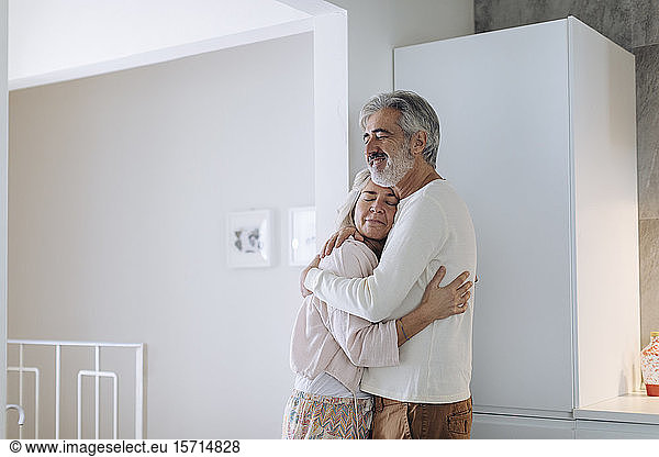 Affectionate mature couple hugging at home