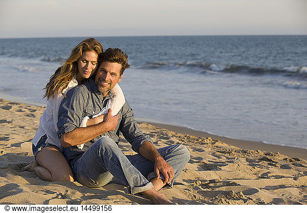 Affectionate Mid-Adult Couple Sitting on Sandy Beach