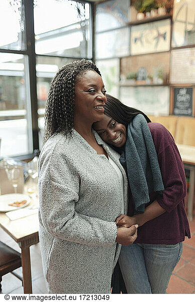 Affectionate mother and daughter hugging in cafe