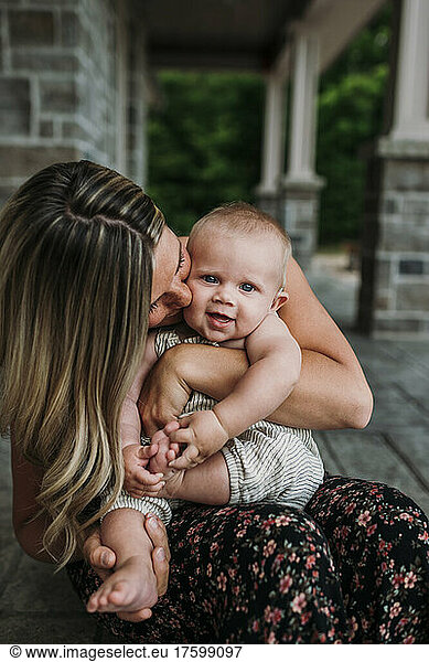 Affectionate mother kissing cute son at porch