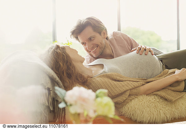 Affectionate pregnant couple laying touching stomach