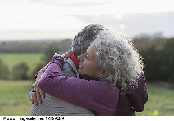 Affectionate senior couple hugging in field