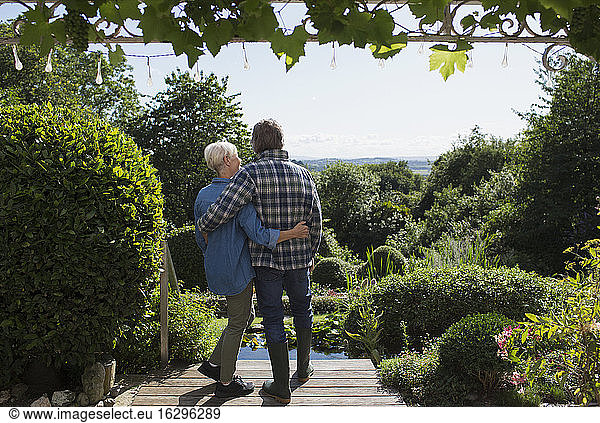 Affectionate senior couple hugging on sunny summer garden patio