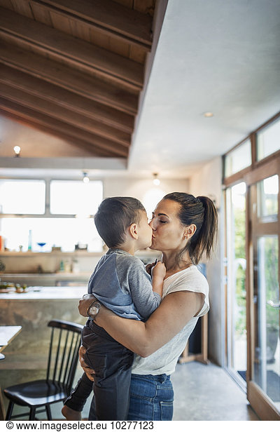 Affectionate woman kissing son at home
