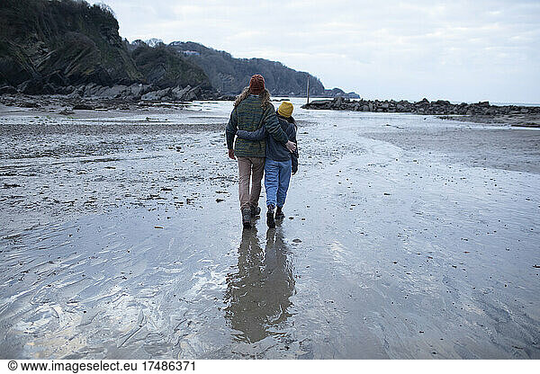 Affectionate young couple walking on wet sand beach