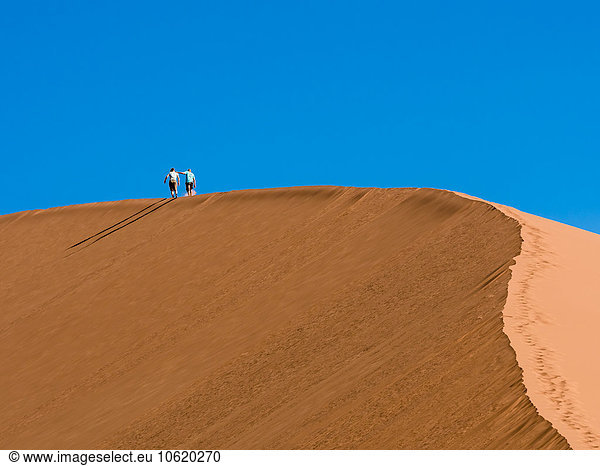 Africa  Namibia  Sossusvlei  Two people hiking in the sand dunes