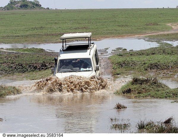 Africa  Tanzania  Serengeti National Park  Safari tourists in an open top land rover crossing a water barrier