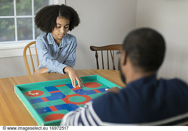 African America ten year-old girl playing board game with father
